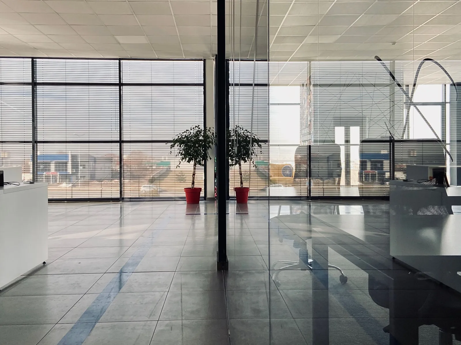 Modern office interior with glass partition, large windows and potted plants