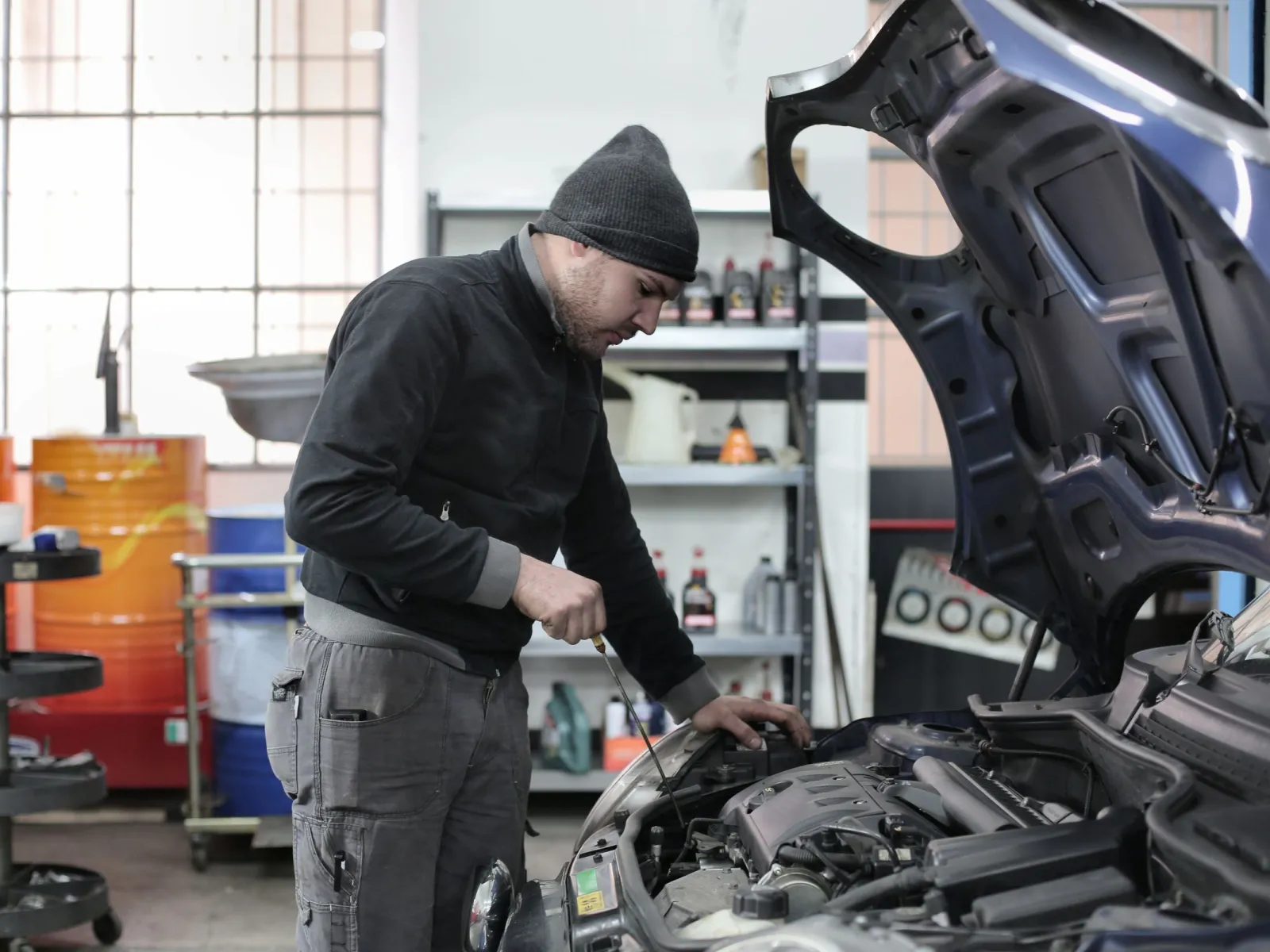 Technician checking the oil level in the engine bay of a blue car