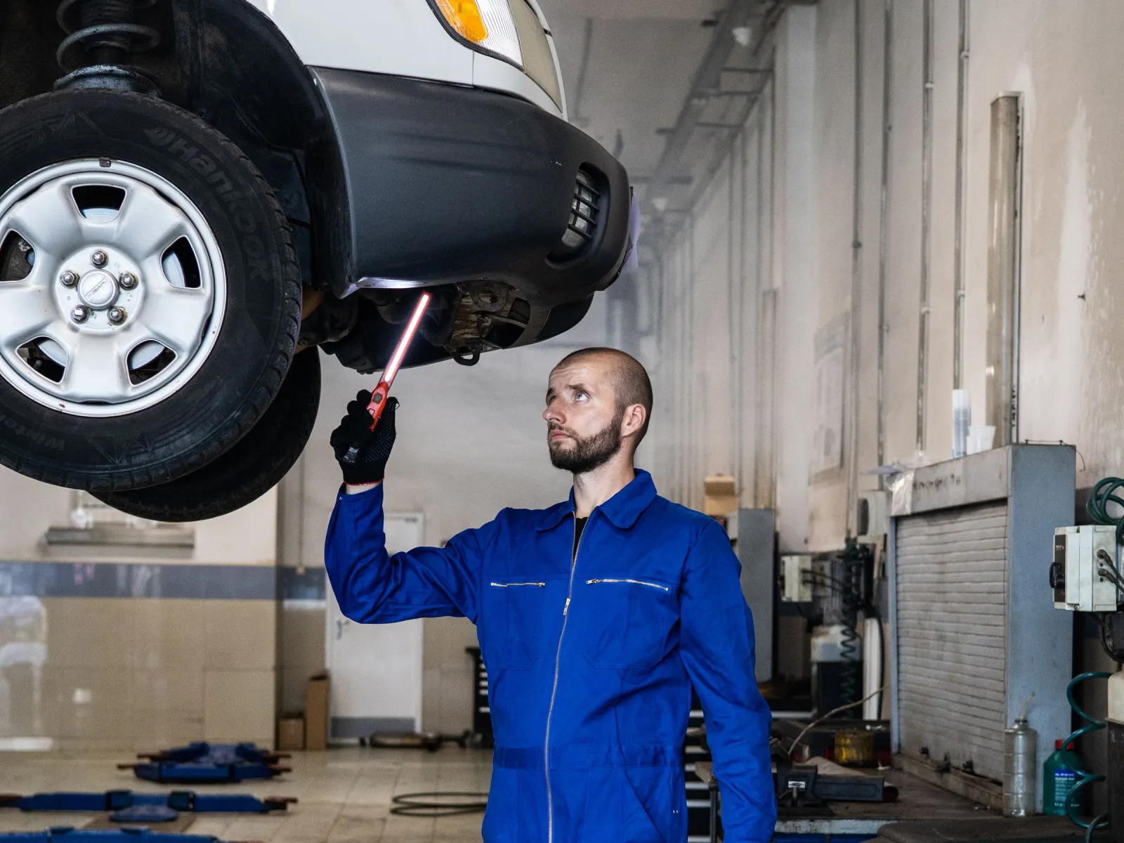 Mechanic shining a worklight under the front of a lifted SUV